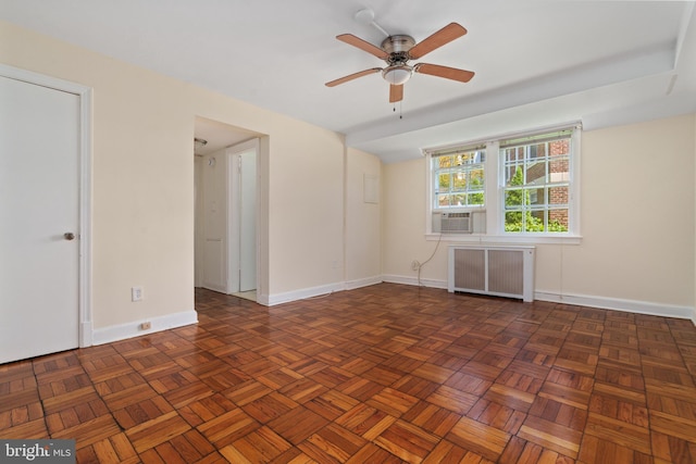 empty room featuring ceiling fan, radiator heating unit, and dark parquet floors