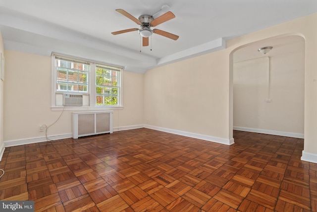 empty room with radiator, ceiling fan, dark parquet floors, and cooling unit