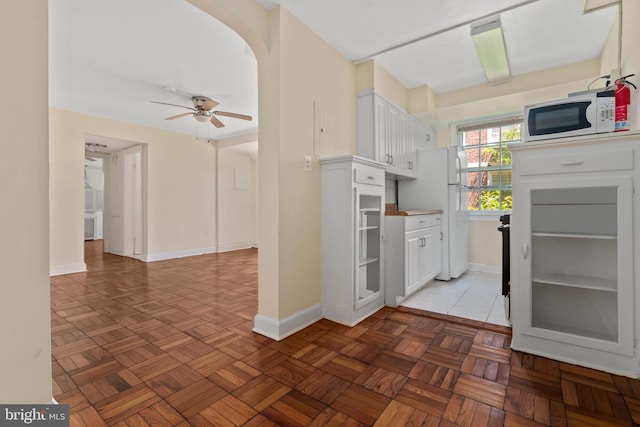 kitchen with white appliances, white cabinetry, and light parquet floors