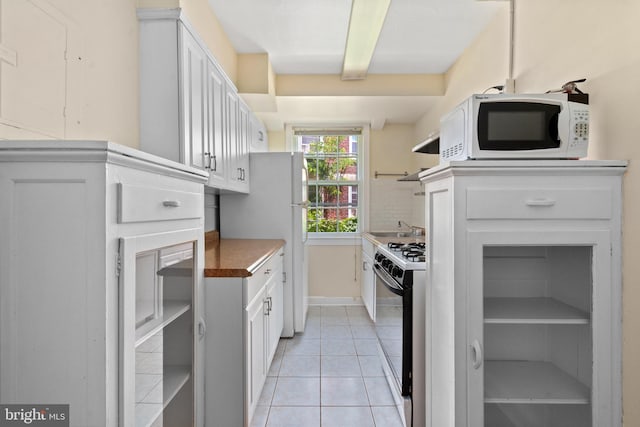 kitchen featuring backsplash, white cabinetry, light tile patterned floors, and white appliances