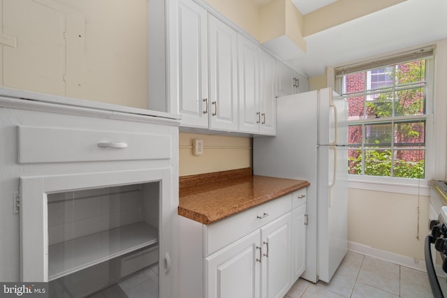 kitchen with light tile patterned floors, white cabinetry, a wealth of natural light, and range