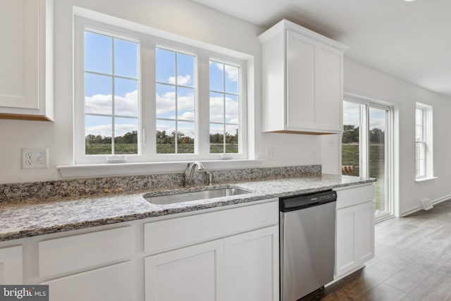 kitchen with stainless steel dishwasher, light stone counters, white cabinetry, and sink