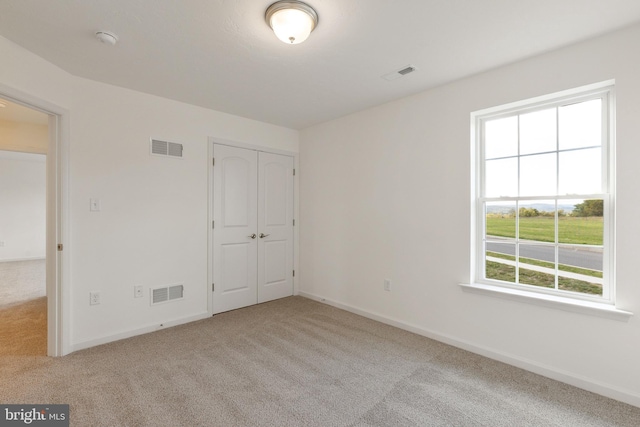 unfurnished bedroom with light colored carpet and a closet