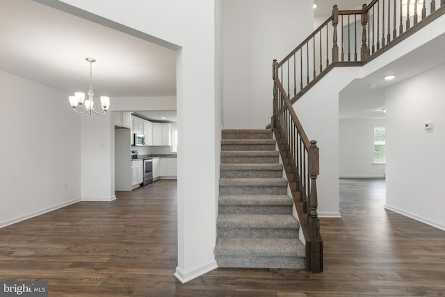 stairway featuring wood-type flooring and a notable chandelier