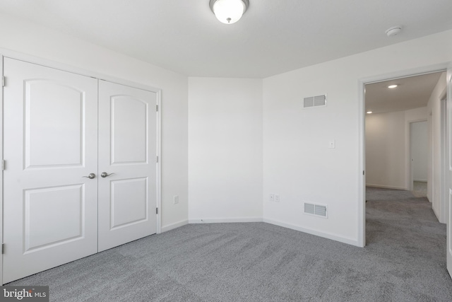 unfurnished bedroom featuring a closet and light colored carpet