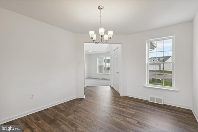 unfurnished dining area with dark hardwood / wood-style floors and an inviting chandelier