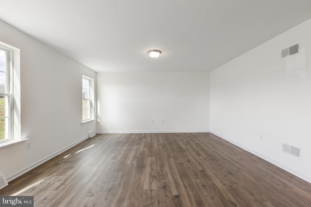 empty room with dark wood-type flooring and a wealth of natural light