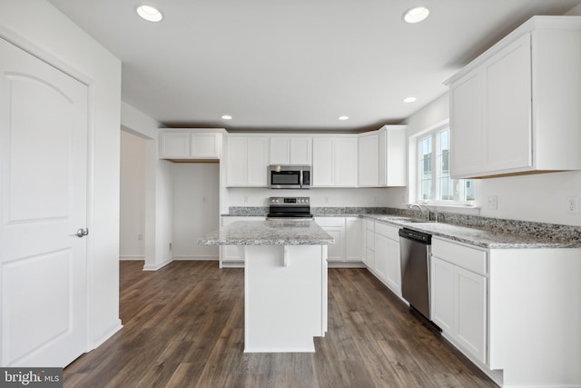 kitchen with white cabinetry, a center island, light stone counters, and appliances with stainless steel finishes