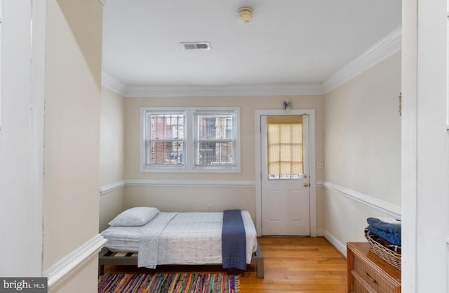 bedroom with ornamental molding and light hardwood / wood-style floors