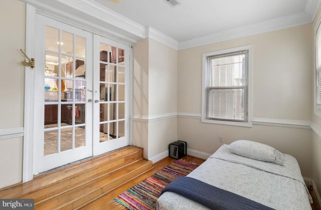 bedroom with crown molding, wood-type flooring, and french doors