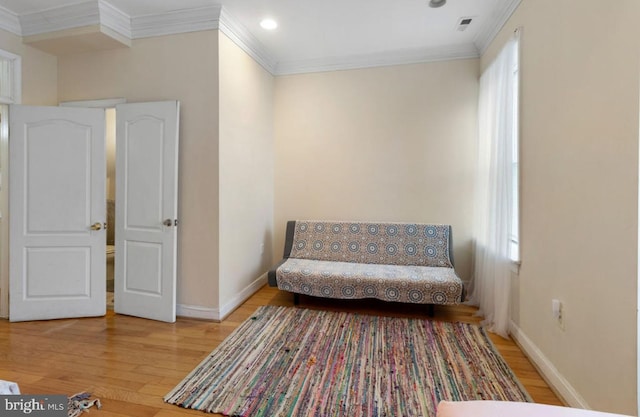 sitting room with a healthy amount of sunlight, wood-type flooring, and ornamental molding