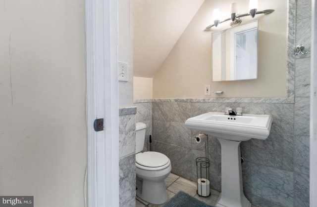 bathroom featuring tile walls, toilet, lofted ceiling, and tile patterned flooring