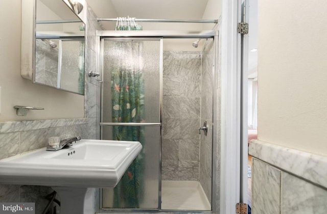 bathroom featuring a shower with door and sink