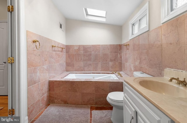 bathroom featuring toilet, vanity, tile walls, and tiled tub