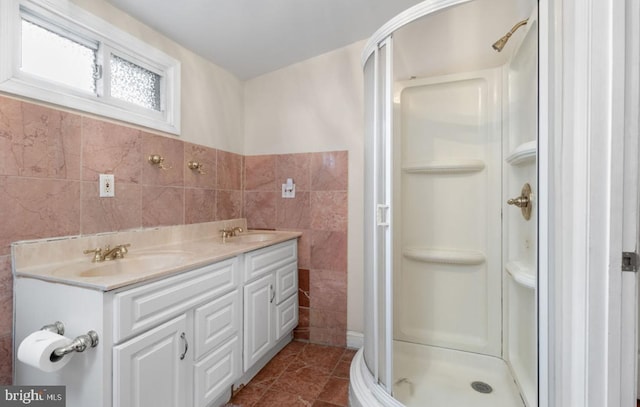 bathroom with a shower with shower door, vanity, tile walls, and tile patterned floors