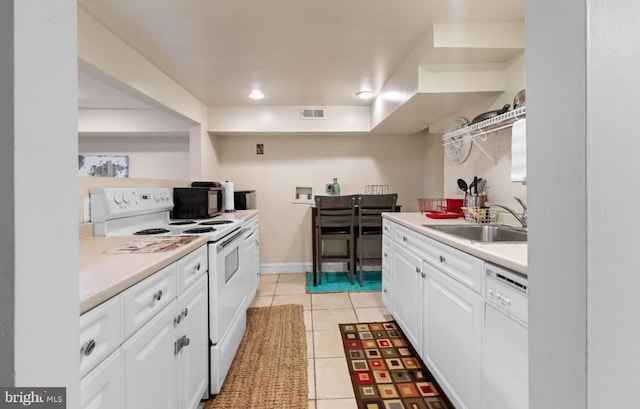 kitchen with light tile patterned flooring, white cabinetry, sink, and white appliances