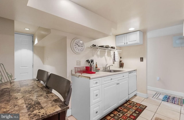 kitchen featuring sink, white dishwasher, white cabinetry, and light tile patterned flooring