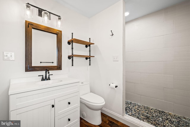 bathroom with vanity, toilet, wood-type flooring, and tiled shower