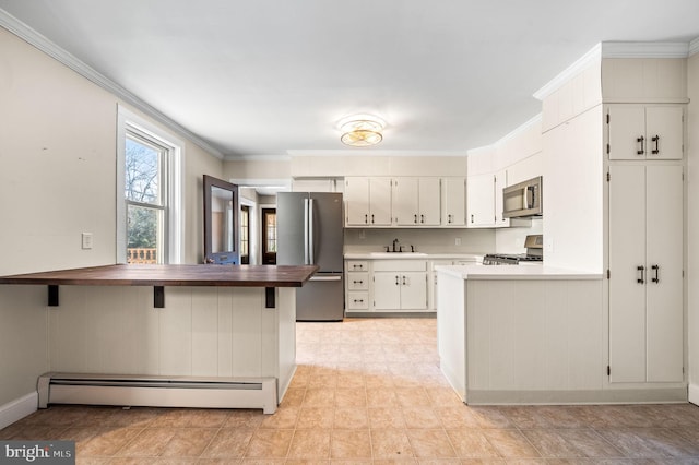 kitchen featuring kitchen peninsula, stainless steel appliances, baseboard heating, crown molding, and white cabinets