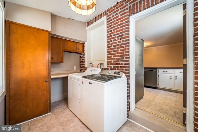 clothes washing area featuring washer and dryer and brick wall