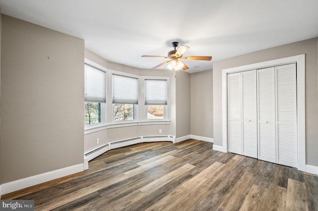 unfurnished bedroom with ceiling fan, a closet, dark hardwood / wood-style floors, and a baseboard heating unit