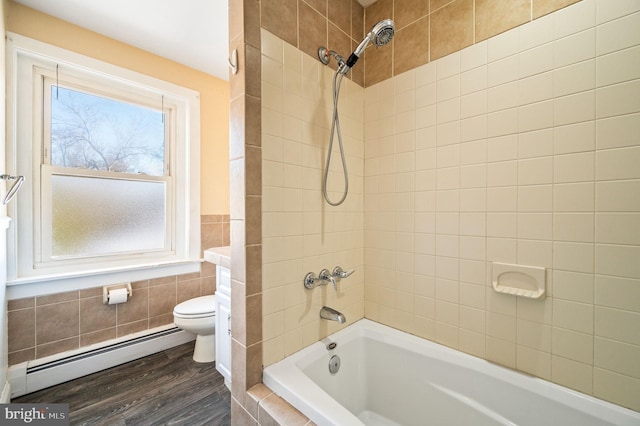 bathroom with wood-type flooring, tiled shower / bath combo, a baseboard radiator, and toilet