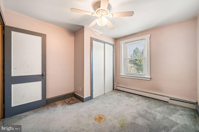 unfurnished bedroom featuring baseboard heating, ceiling fan, a closet, and carpet floors