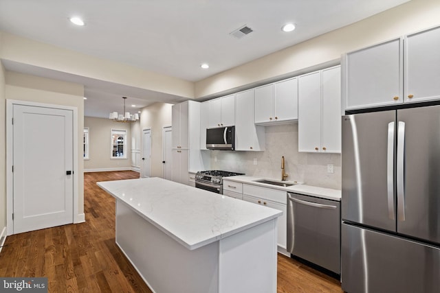 kitchen featuring appliances with stainless steel finishes, white cabinetry, sink, hanging light fixtures, and a center island