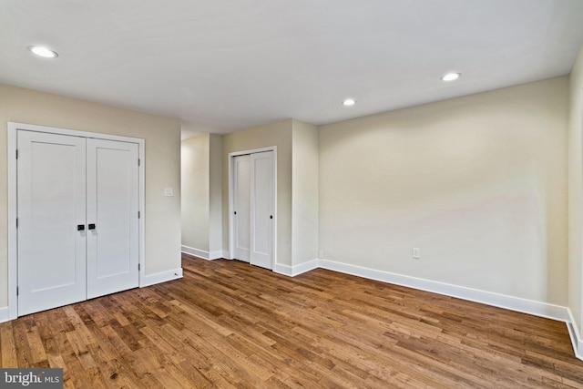 unfurnished bedroom featuring multiple closets and wood-type flooring