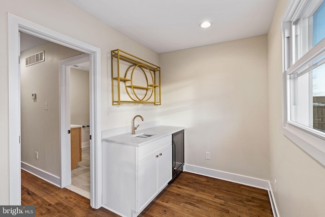 bar with sink, dark wood-type flooring, white cabinets, and decorative light fixtures