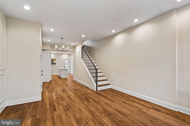 unfurnished living room featuring an inviting chandelier and hardwood / wood-style floors