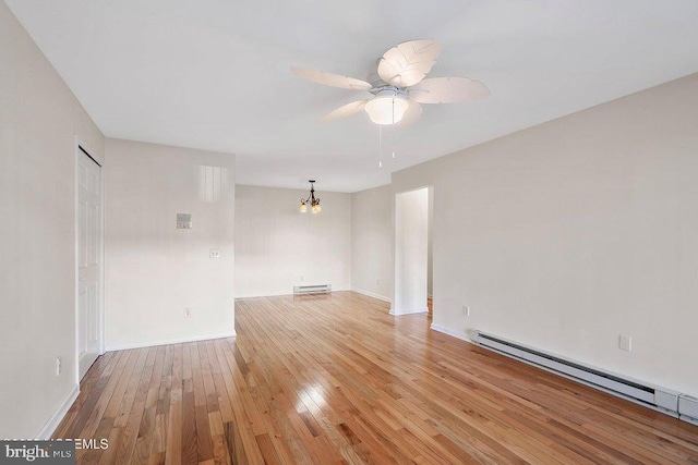 spare room featuring ceiling fan with notable chandelier, light wood-type flooring, and a baseboard radiator