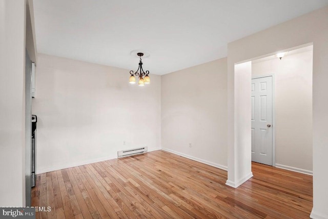 unfurnished room featuring an inviting chandelier, light wood-type flooring, and a baseboard radiator