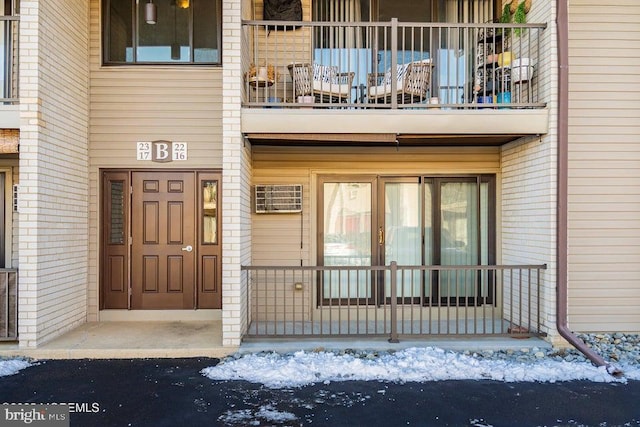 snow covered property entrance with a balcony