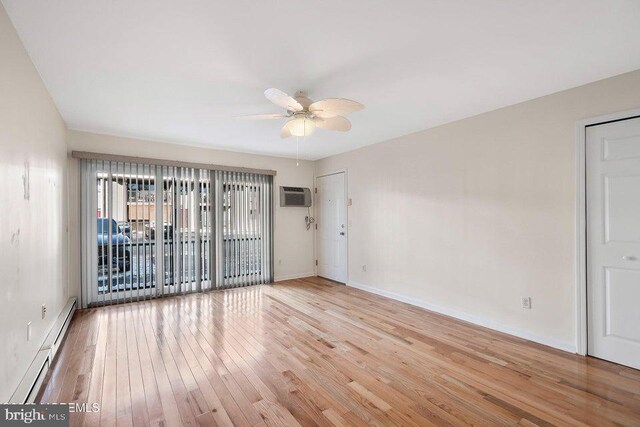 empty room featuring a baseboard radiator, a wall unit AC, ceiling fan, and light hardwood / wood-style flooring