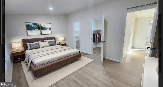 bedroom with light hardwood / wood-style floors, a walk in closet, and a closet