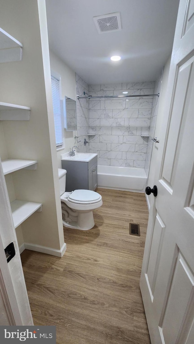 full bathroom with wood-type flooring, vanity, toilet, and tiled shower / bath combo