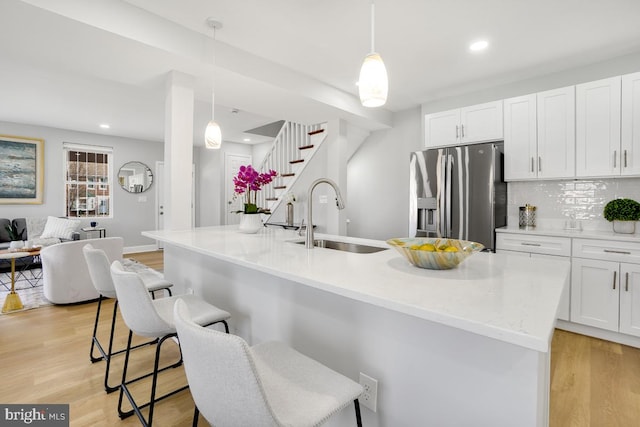 kitchen with a breakfast bar, stainless steel fridge, sink, and hanging light fixtures