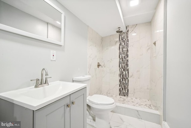 bathroom featuring a tile shower, vanity, and toilet