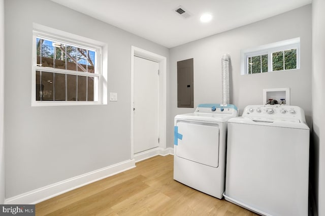 laundry area featuring electric panel, light hardwood / wood-style flooring, and washer and clothes dryer