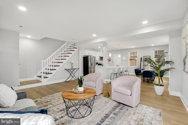 living room featuring sink and light hardwood / wood-style flooring