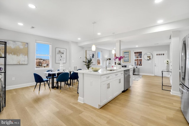 kitchen with white cabinetry, sink, hanging light fixtures, a kitchen island with sink, and appliances with stainless steel finishes