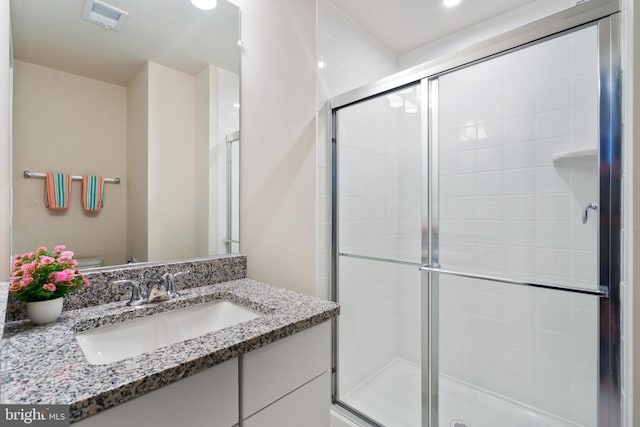 bathroom featuring vanity, toilet, and a shower with shower door