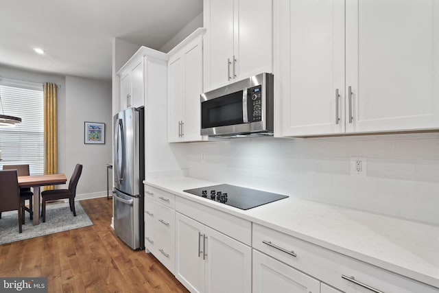 kitchen with decorative backsplash, light stone countertops, dark hardwood / wood-style flooring, white cabinetry, and stainless steel appliances