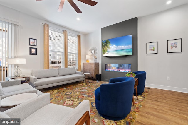 living room featuring ceiling fan, a large fireplace, wood-type flooring, and a wealth of natural light