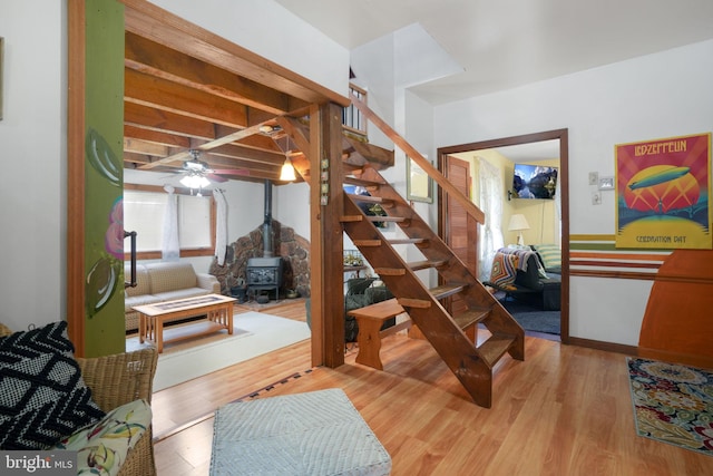 bedroom with beamed ceiling, wood-type flooring, and a wood stove