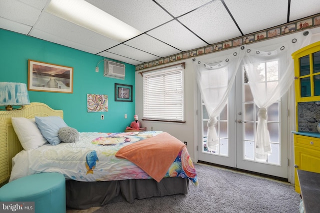 bedroom featuring a wall unit AC, a drop ceiling, and access to outside