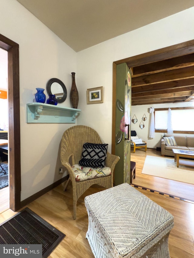 living area with beam ceiling and light wood-type flooring