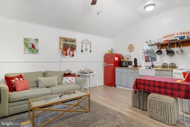 living room with light hardwood / wood-style floors, vaulted ceiling, and sink