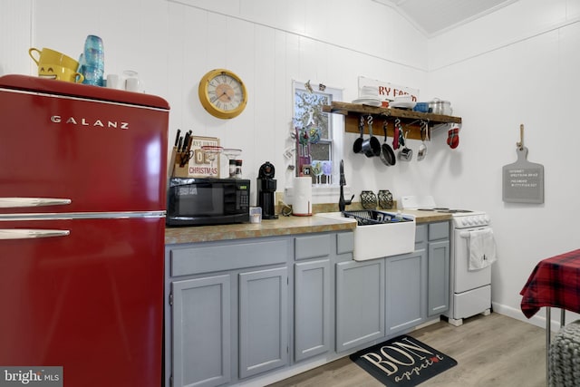 kitchen with gray cabinetry, refrigerator, light hardwood / wood-style floors, lofted ceiling, and electric stove